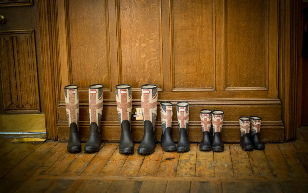 Four pairs of Union Jack wellington boots neatly arranged on a wooden floor indoors.