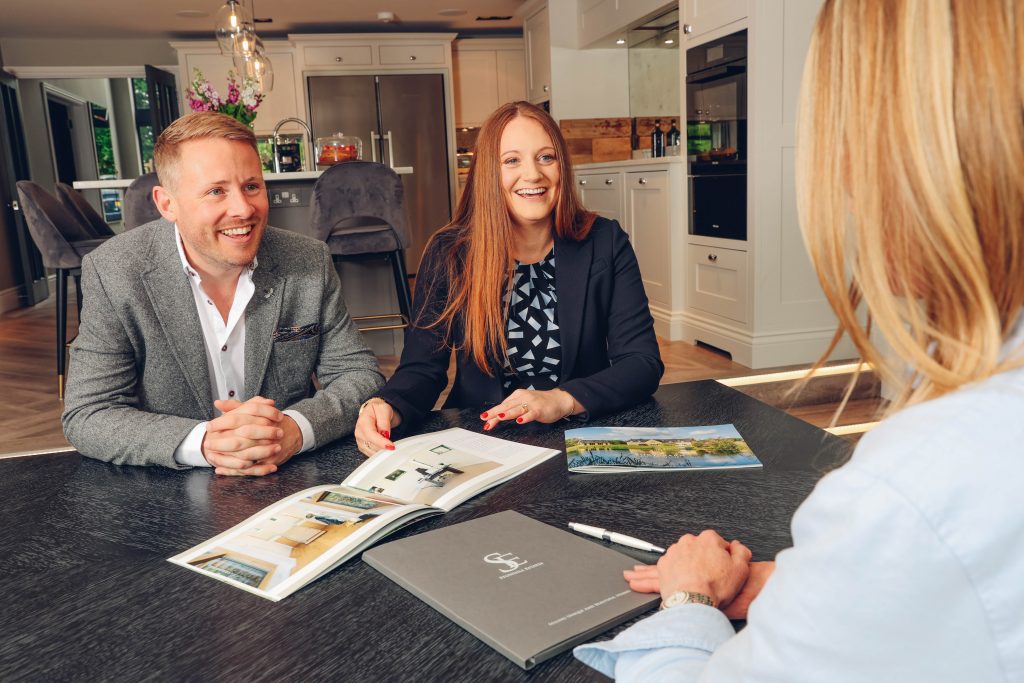 Homebuyers reviewing a property brochure during a consultation with an estate agent.